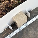 Concrete blocks and metal stakes to secure rodent barrier from high winds